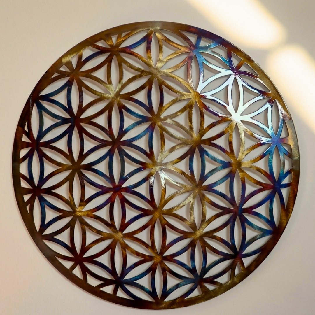 Disque décoratif rond en métal avec motif fleur de vie en perforations, fini multicolore doré et bleu, motifs géométriques entrelacés.