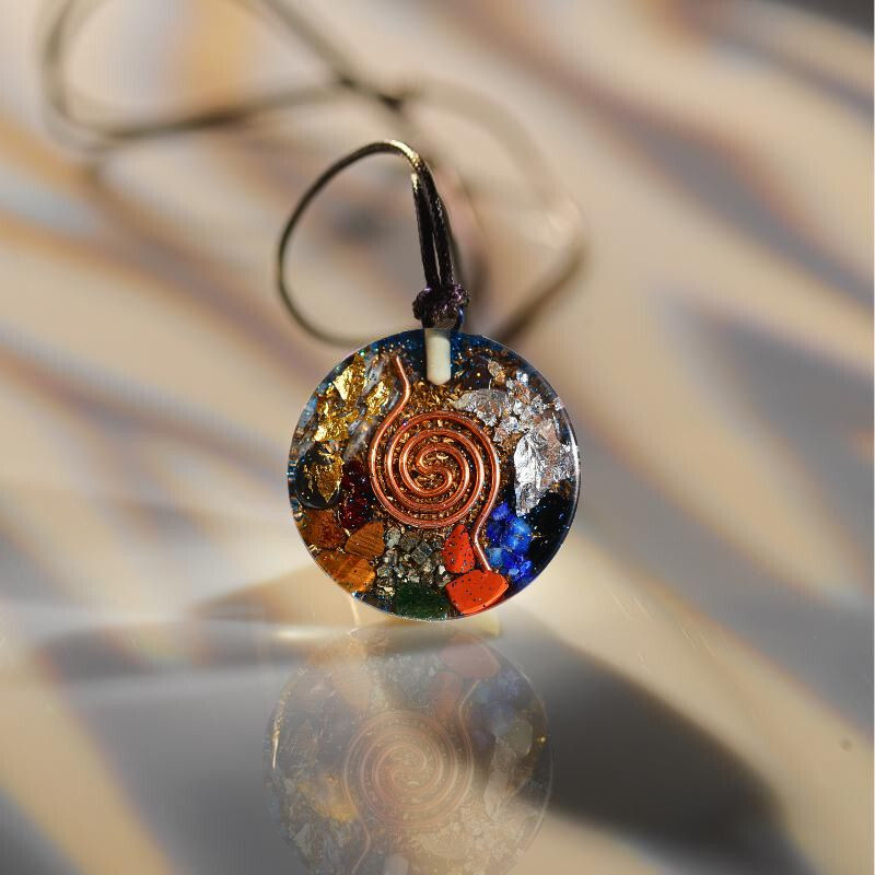 Pendentif générateur d’orgone artisanal avec cristaux visibles (quartz, améthyste et minéraux) intégrés dans une résine et des métaux